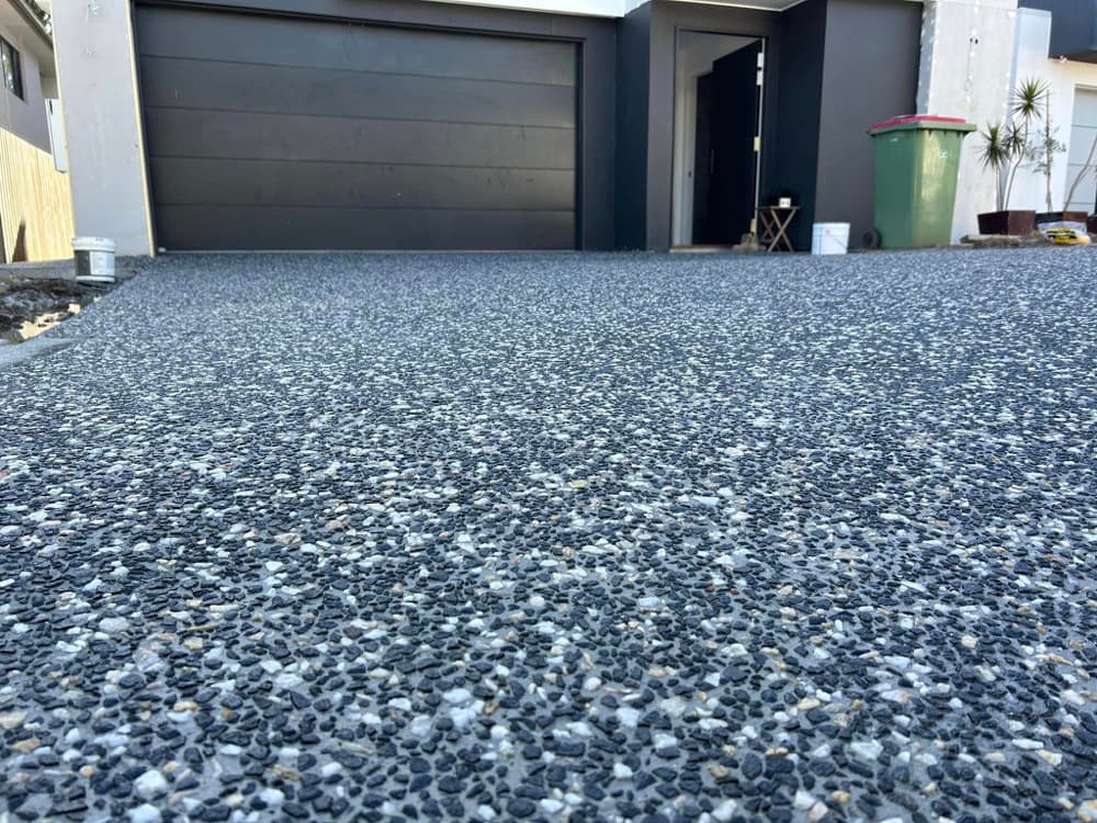 Close-up of a freshly exposed aggregate finish in front of a garage