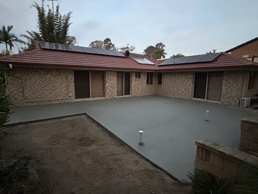New concrete courtyard slab enclosed by a brick house