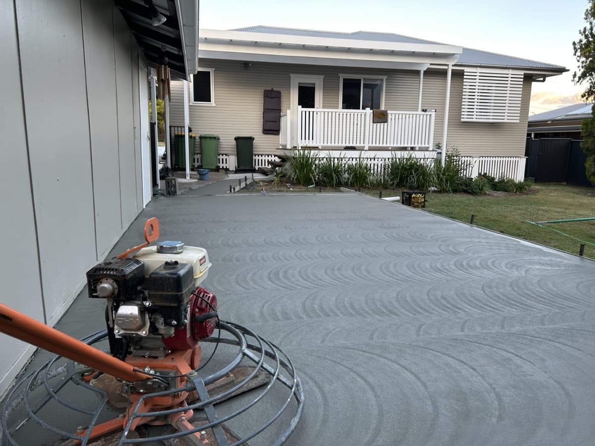 Power trowel smoothing a large new slab beside a house