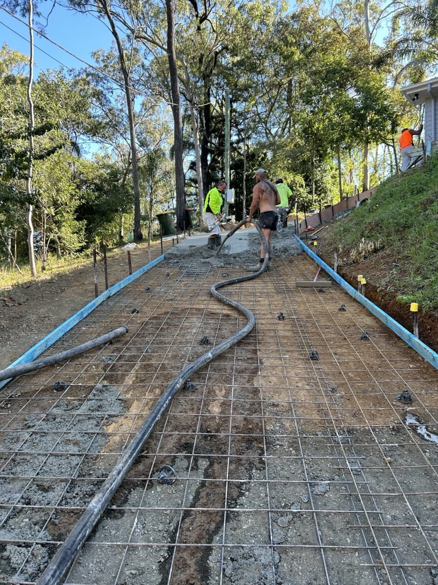 Crew pumping concrete onto a reinforced slab on a sloping block