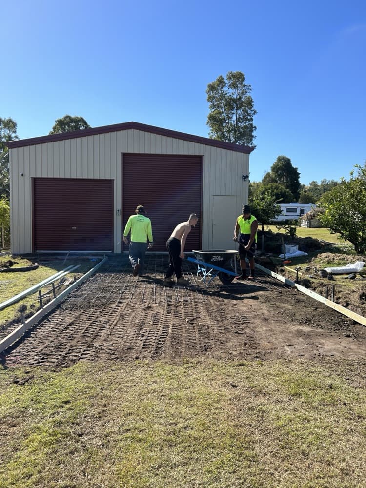Crew pouring a slab in front of a large steel shed
